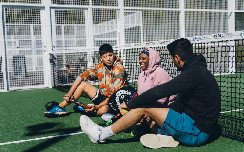 Tre ungdomar som sitter på en tennisbana