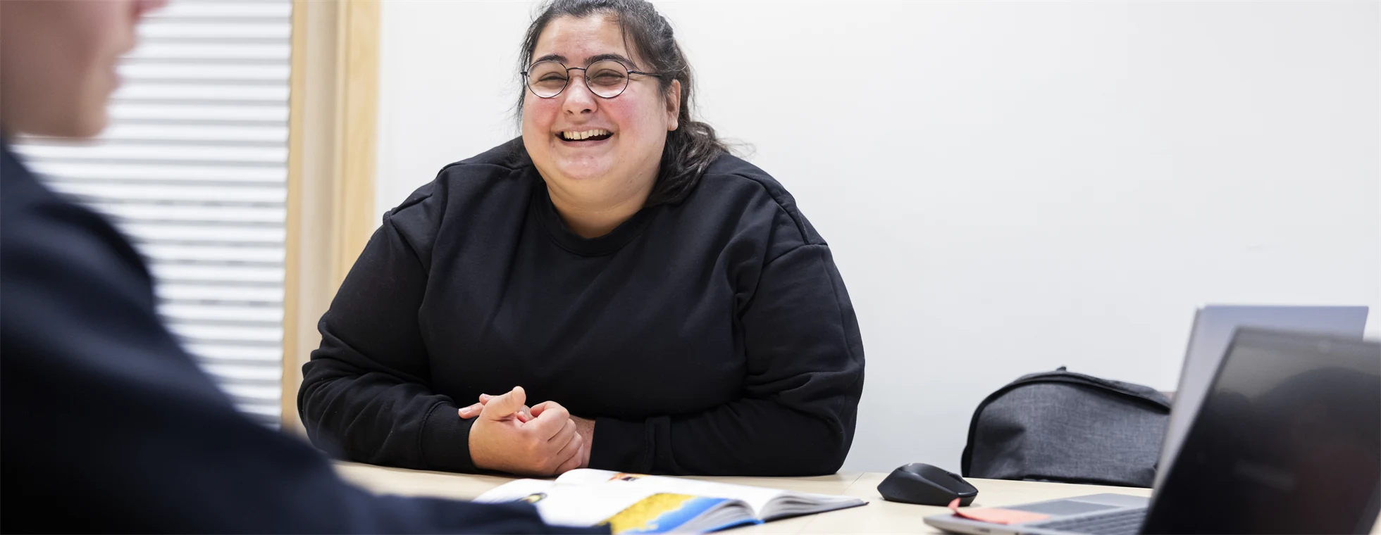 En leende lärare tittar på sin elev som skriver på en dator