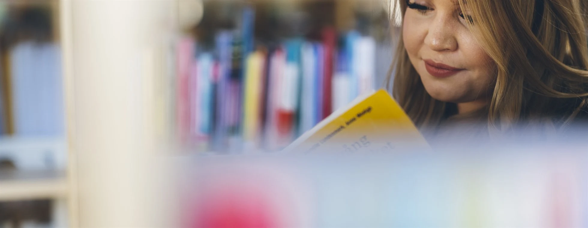 Tjej som läser en bok på ett bibliotek