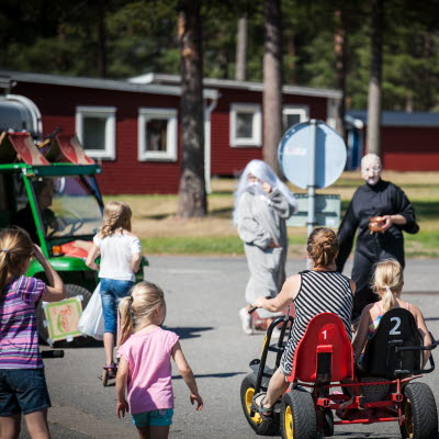 Barn och vuxna sitter i en trampbil på Byske camping. 