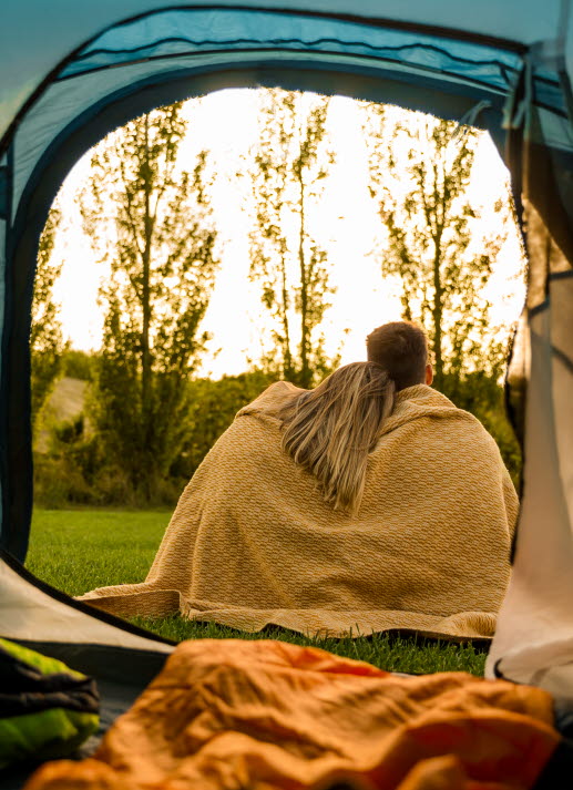 Två personer utanför ett tält tittar på solnedgången