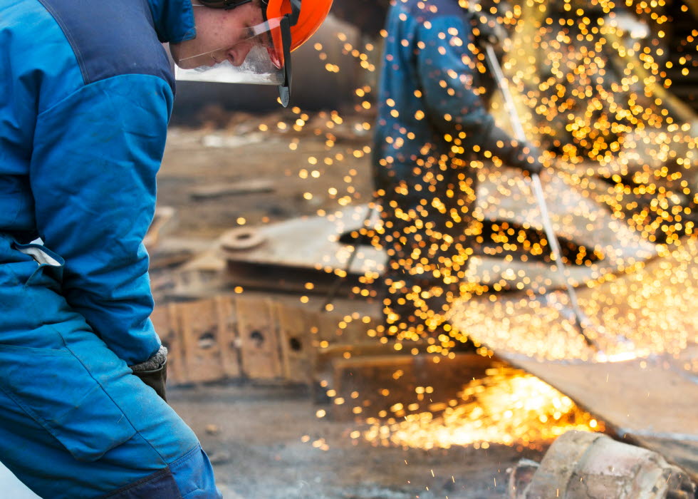 Two men welding on a tractor